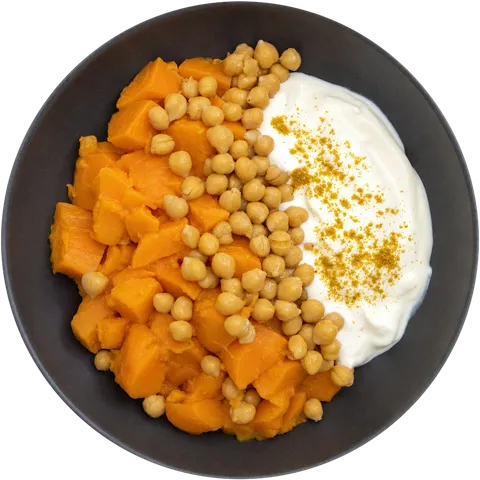 Assiette de patate douce en morceaux, pois chiches et sauce au skyr saupoudrée de curry